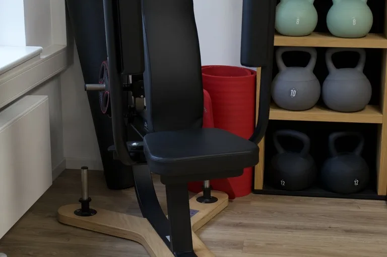 Kraftgerät neben dem Regal mit Kettlebells