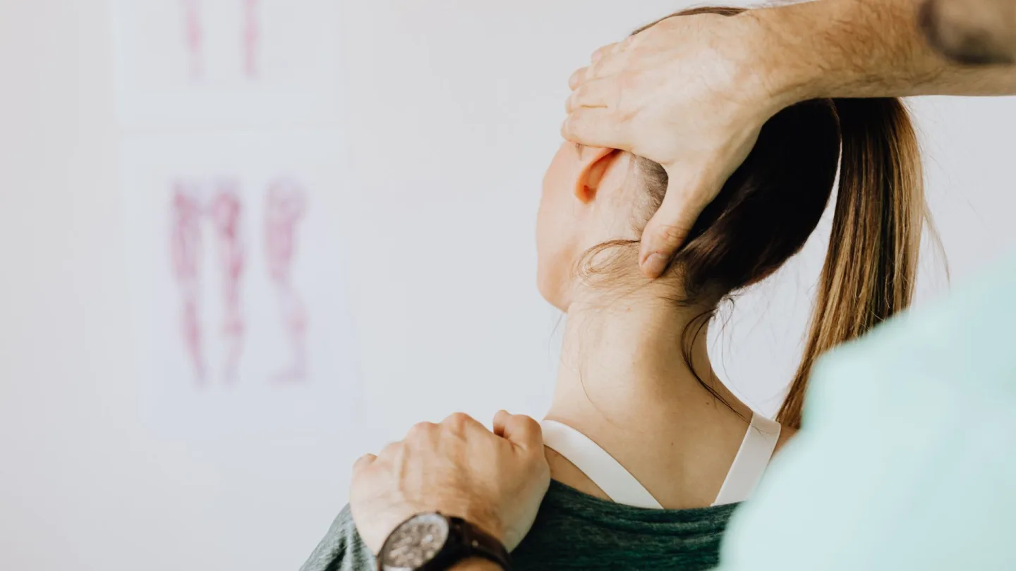 Osteopathische Behandlung: Hände an Hinterkopf und Schulter einer Patientin