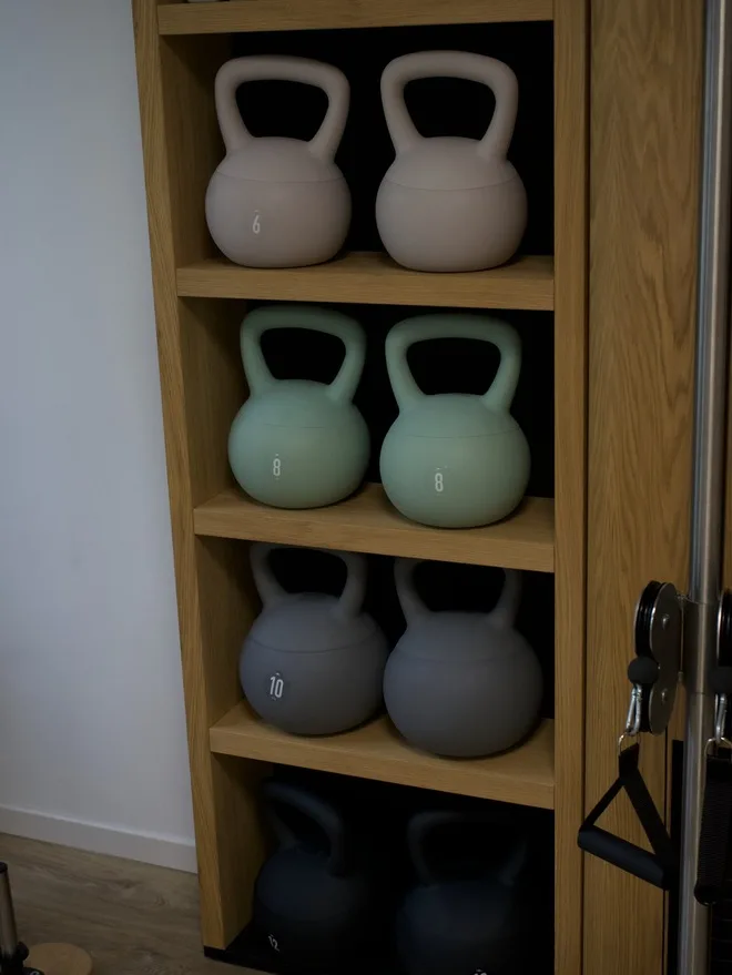 Kettlebells in verschiedenen Gewichten in einem Holzregal